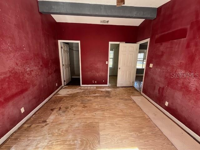 interior space with baseboards, beam ceiling, and visible vents