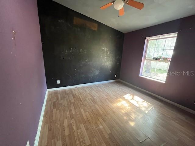 unfurnished room featuring a ceiling fan, lofted ceiling, baseboards, and wood finished floors