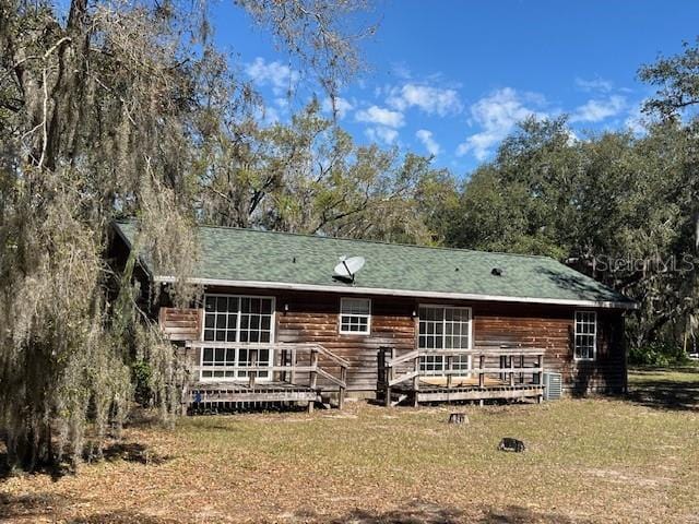 rear view of property featuring a yard and a wooden deck