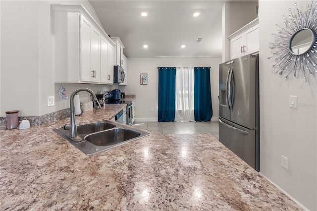 kitchen with a sink, recessed lighting, stainless steel appliances, white cabinets, and light stone countertops