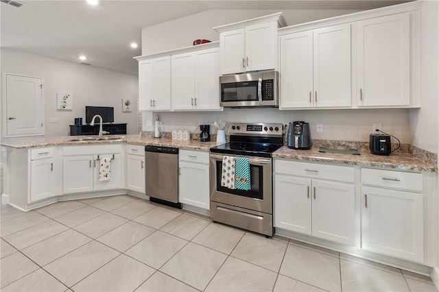 kitchen featuring visible vents, a peninsula, a sink, stainless steel appliances, and white cabinetry