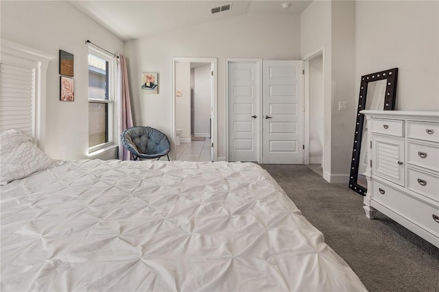 carpeted bedroom featuring ensuite bath, vaulted ceiling, baseboards, and visible vents