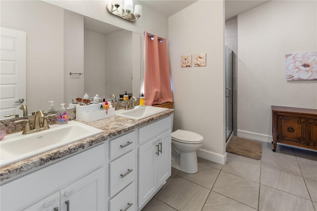 bathroom featuring a shower stall, toilet, double vanity, and a sink