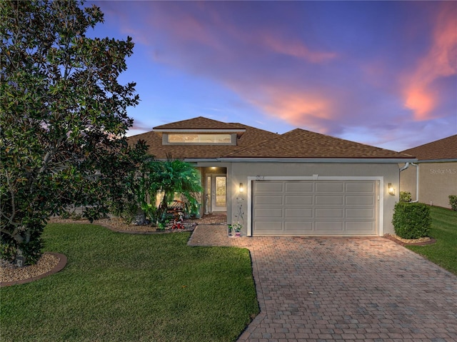 view of front facade with a garage, a front yard, driveway, and stucco siding