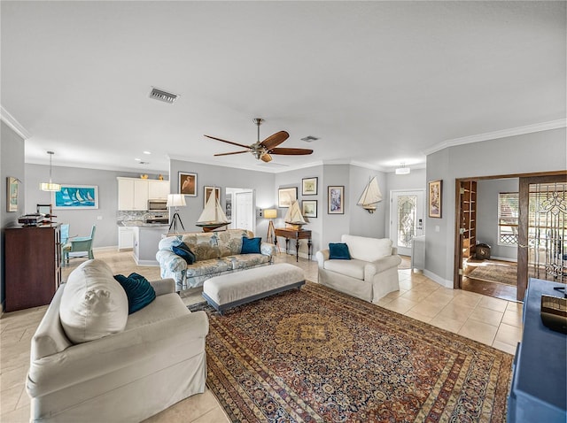 living room featuring light tile patterned flooring, visible vents, ceiling fan, and ornamental molding