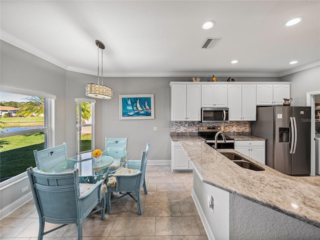 kitchen with light stone countertops, stainless steel appliances, white cabinets, crown molding, and backsplash