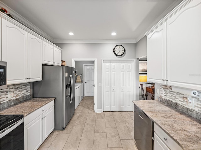 kitchen with washing machine and clothes dryer, stainless steel appliances, white cabinetry, crown molding, and tasteful backsplash