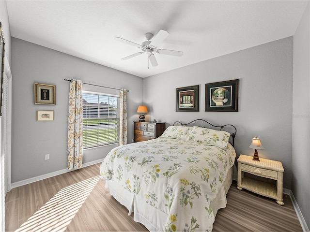 bedroom featuring baseboards, wood finished floors, and a ceiling fan