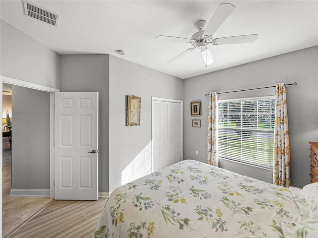 bedroom with visible vents, baseboards, light wood-type flooring, a closet, and a ceiling fan