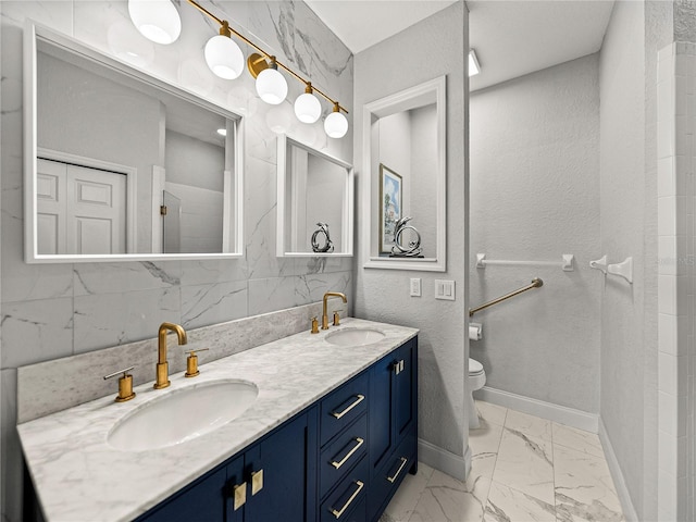 full bath featuring double vanity, marble finish floor, toilet, and a sink