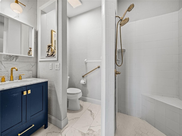 bathroom featuring a tile shower, marble finish floor, toilet, and baseboards