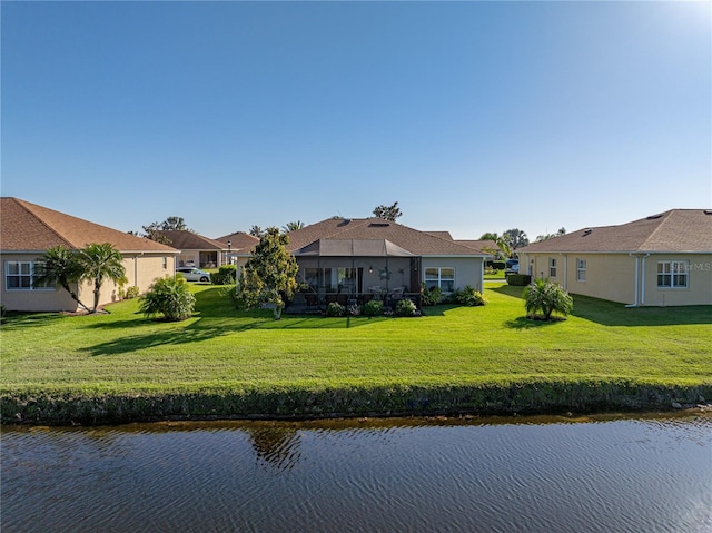 back of property with a residential view, a lawn, stucco siding, and a water view