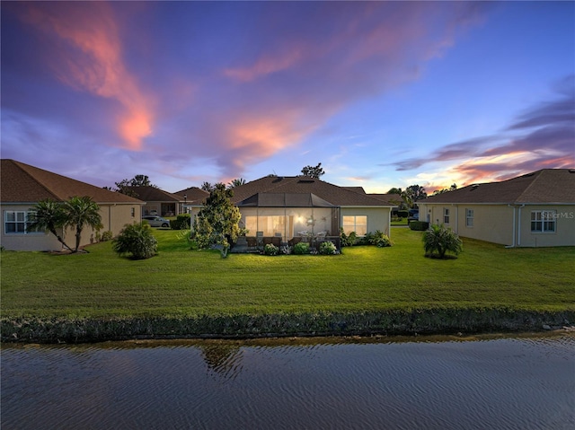 view of front of house featuring stucco siding, a yard, and a water view