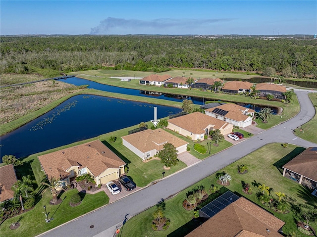 drone / aerial view featuring a residential view, a forest view, and a water view