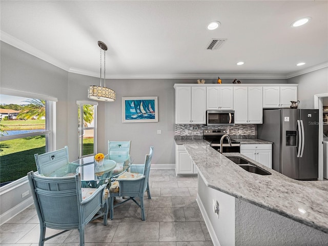 kitchen featuring backsplash, crown molding, light stone countertops, white cabinets, and stainless steel appliances
