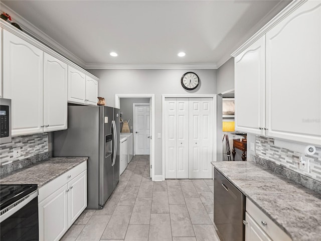 kitchen featuring washer and clothes dryer, white cabinets, stainless steel appliances, and ornamental molding