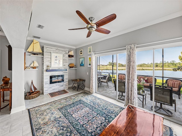 living room featuring visible vents, ornamental molding, ceiling fan, a water view, and a glass covered fireplace