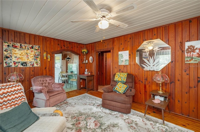 living area featuring ceiling fan, visible vents, arched walkways, and wood finished floors