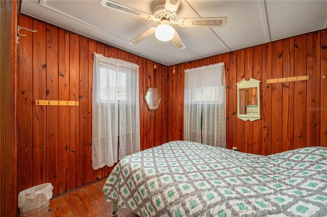 bedroom featuring ceiling fan, wood finished floors, and wood walls