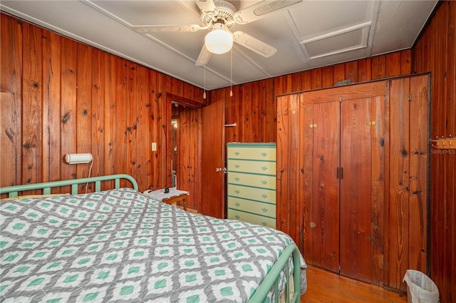 bedroom with wood finished floors, wood walls, and a ceiling fan
