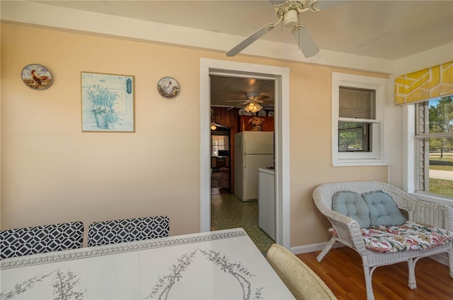 bedroom with baseboards, freestanding refrigerator, a ceiling fan, and wood finished floors