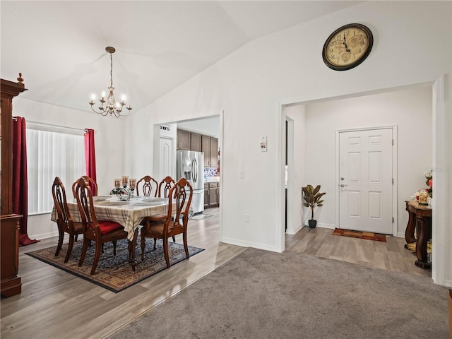 dining room featuring a notable chandelier, lofted ceiling, and wood finished floors