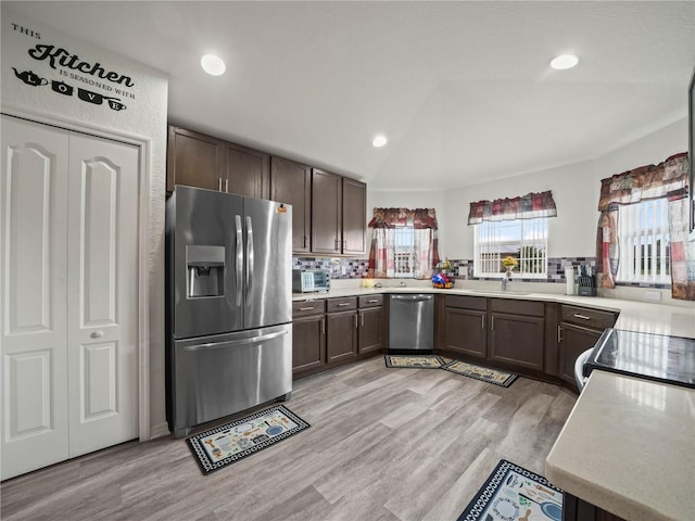 kitchen with light wood finished floors, dark brown cabinets, appliances with stainless steel finishes, and lofted ceiling