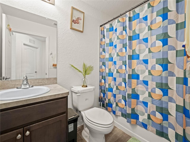 bathroom with toilet, vanity, a shower with curtain, a textured wall, and a textured ceiling