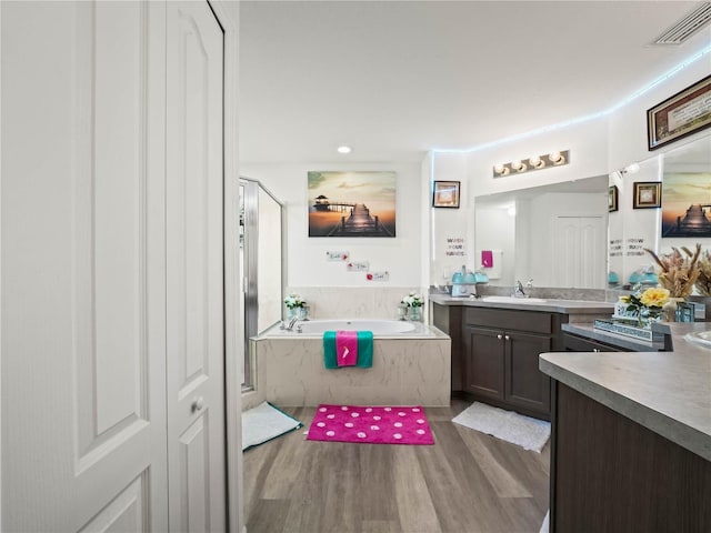 bathroom with visible vents, wood finished floors, a bath, and vanity