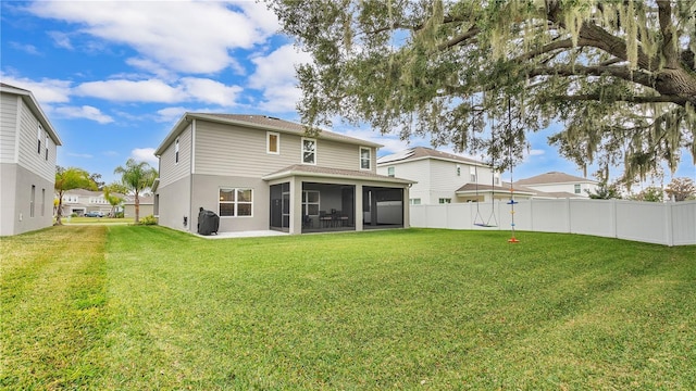 rear view of property featuring a yard, fence, and a sunroom