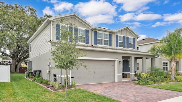 view of front facade with stucco siding, a front lawn, decorative driveway, fence, and an attached garage