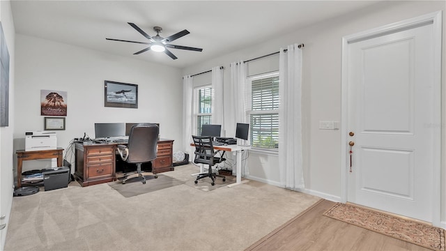 carpeted office featuring baseboards, wood finished floors, and a ceiling fan