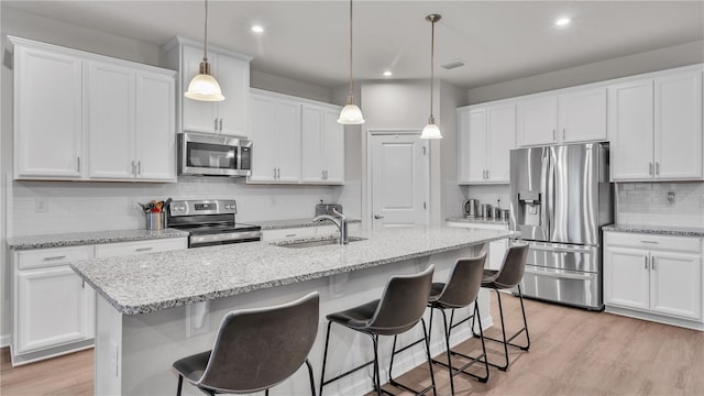 kitchen with a sink, white cabinets, light wood-style floors, and stainless steel appliances