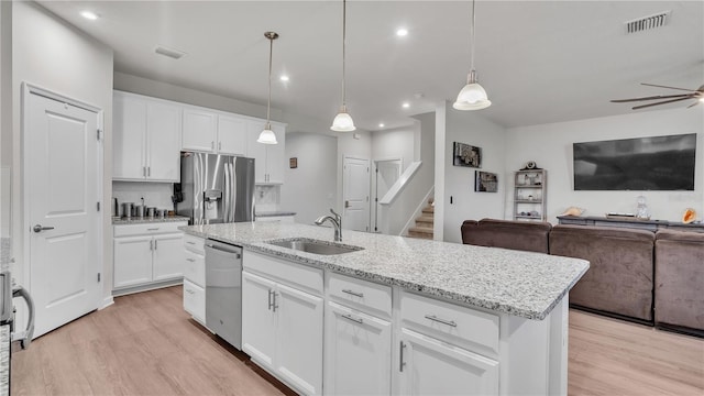 kitchen featuring visible vents, light wood-type flooring, a sink, open floor plan, and appliances with stainless steel finishes