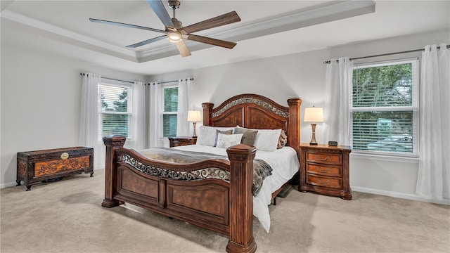 bedroom with light carpet, a ceiling fan, a tray ceiling, crown molding, and baseboards