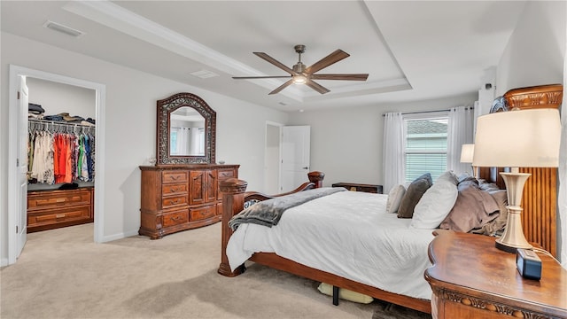 bedroom with visible vents, a closet, light carpet, a walk in closet, and a raised ceiling