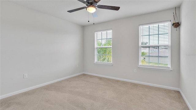 carpeted spare room featuring baseboards and ceiling fan