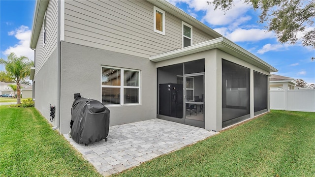 back of house with a yard, a patio, a sunroom, and stucco siding