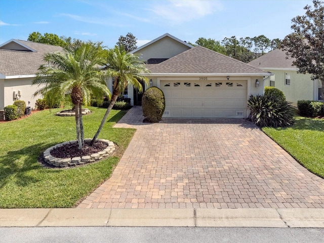 ranch-style home featuring stucco siding, a shingled roof, decorative driveway, and a front yard