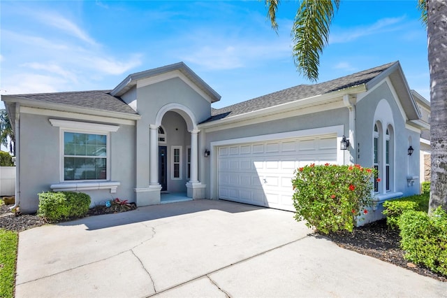 ranch-style home featuring concrete driveway, a garage, roof with shingles, and stucco siding