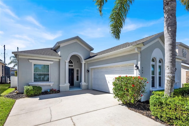 single story home with stucco siding, roof with shingles, concrete driveway, and an attached garage