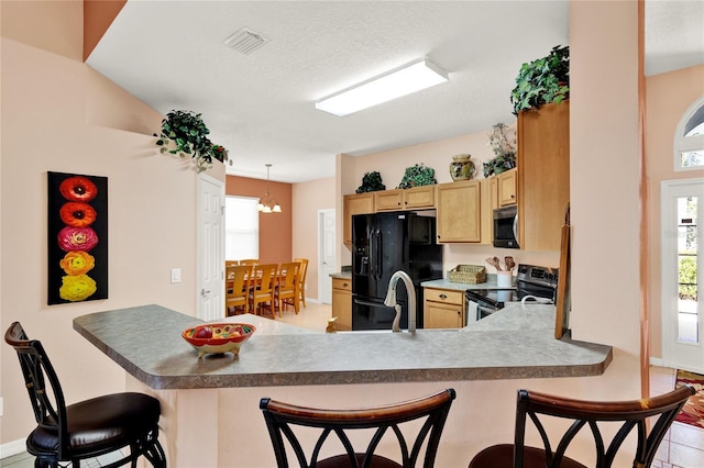 kitchen featuring a breakfast bar area, a healthy amount of sunlight, visible vents, a peninsula, and stainless steel appliances