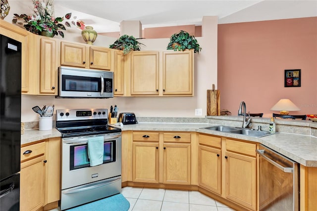 kitchen with a peninsula, light brown cabinetry, appliances with stainless steel finishes, and a sink