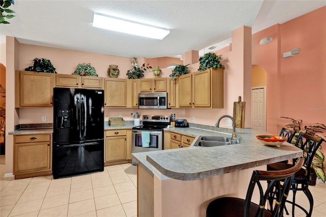 kitchen featuring a sink, a peninsula, light tile patterned floors, and stainless steel appliances