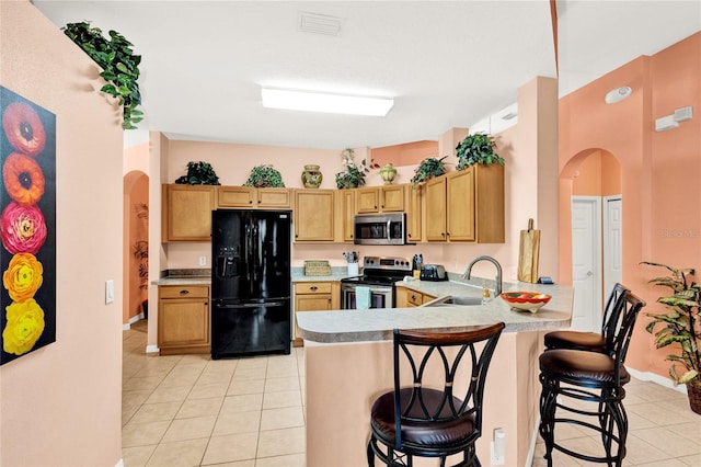 kitchen featuring a sink, arched walkways, appliances with stainless steel finishes, and light tile patterned floors