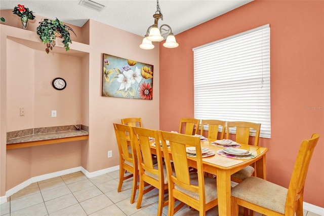 dining space featuring light tile patterned floors, visible vents, baseboards, and built in desk