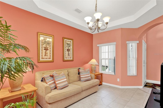 living area featuring visible vents, baseboards, a chandelier, arched walkways, and a raised ceiling