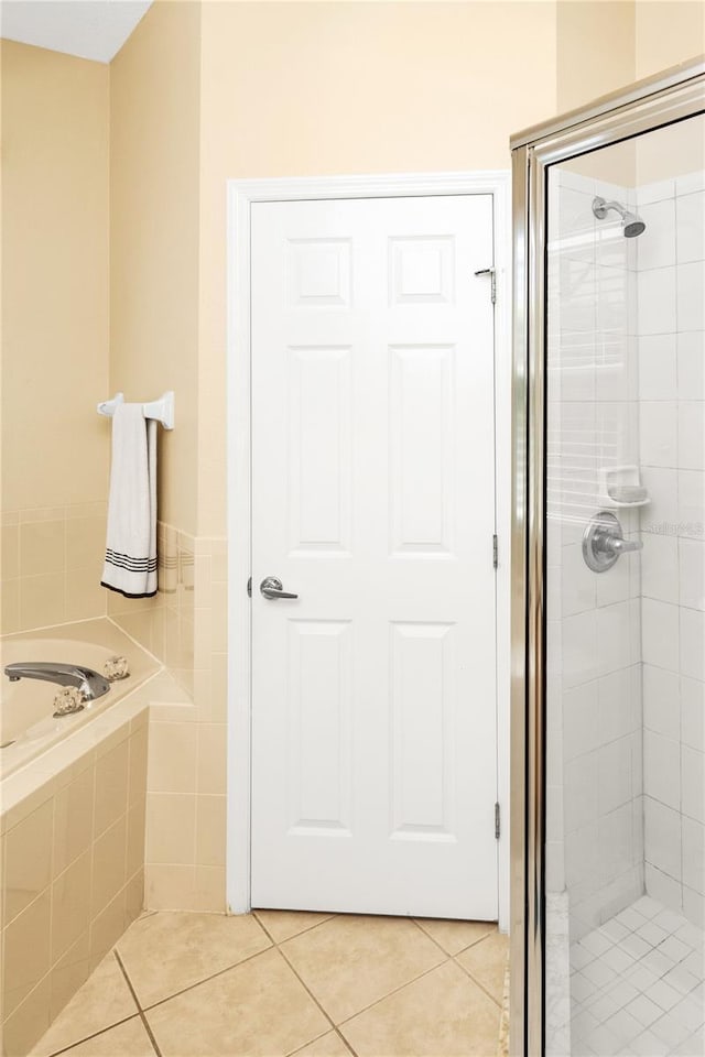 bathroom featuring tile patterned flooring, a shower stall, and a garden tub