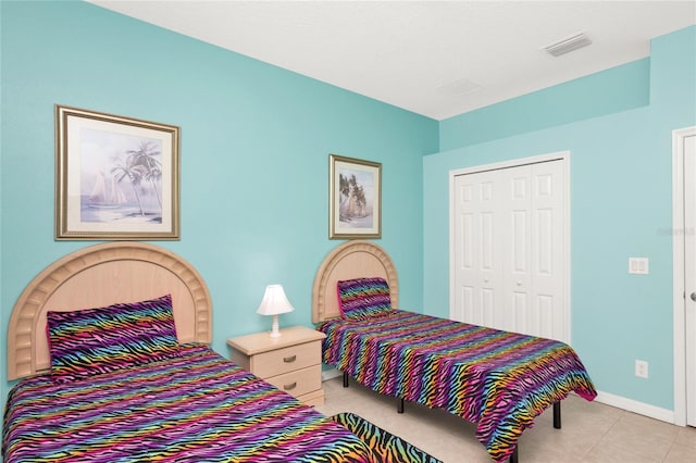 bedroom with light tile patterned floors, visible vents, a closet, and baseboards