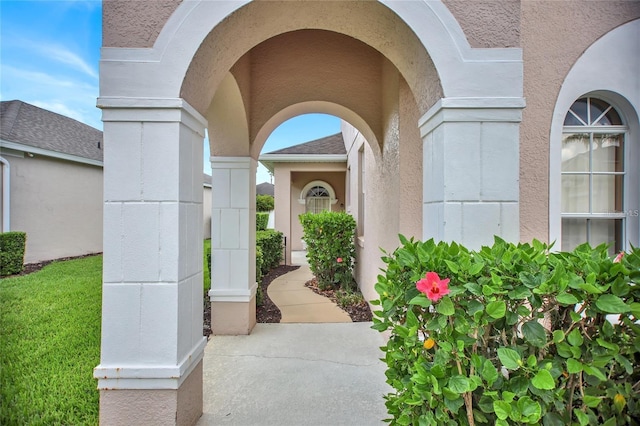 view of exterior entry featuring stucco siding and roof with shingles